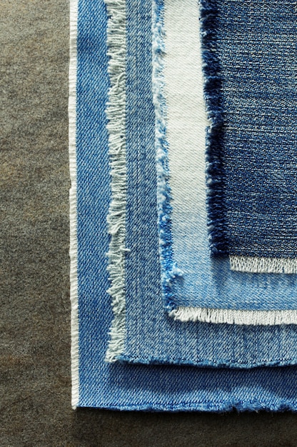 Close-up shot of different denim fabrics showcasing various textures, colors, and blends, including hemp denim, Tencel denim, and recycled denim. Labels indicating eco-friendly credentials are visible.