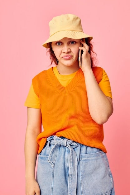 A close-up shot of a woman's outfit featuring a bright orange blazer paired with a simple white t-shirt and high-waisted denim jeans, showcasing how a single bold piece can elevate a casual look.