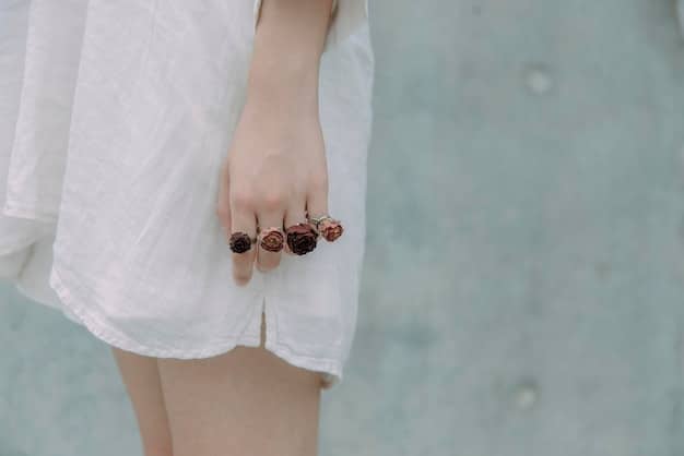 A close-up shot of a woman's hands adorned with multiple statement rings on each finger. The rings are a mix of vintage and modern designs, featuring different metals and colorful gemstones. The background is blurred, focusing on the intricate details of the rings.
