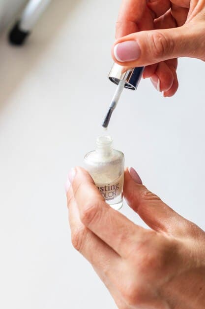 Hands applying a very thin coat of nail polish, almost transparent, on a nail. The focus is on the thinness of the application and the even distribution of the product.