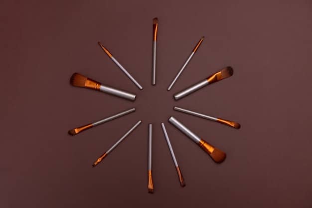 A variety of bronzer brushes in different shapes and sizes laid out on a vanity. The brushes are surrounded by makeup palettes and compacts.