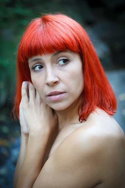 Close-up of a woman with dark brown hair featuring thick, vibrant copper chunky highlights that frame her face.