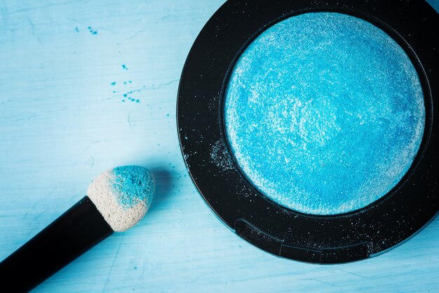 An overhead shot of a makeup artist using a large, fluffy powder brush to gently apply translucent powder to a client's face, with a focus on the soft diffusion of light and the even distribution of the powder.