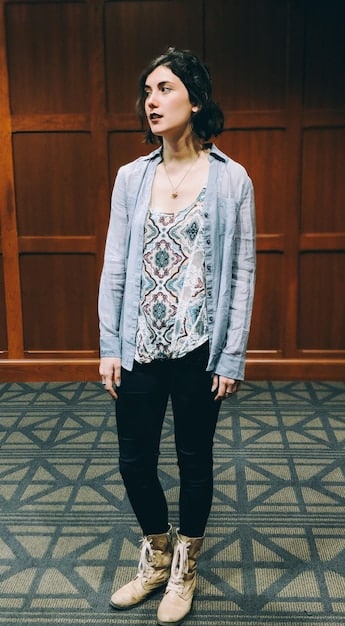A young celebrity wearing an unconventional, gender-neutral outfit on the red carpet. The outfit includes a unique blazer, wide-leg pants, and bold accessories, showcasing a departure from traditional red carpet attire.